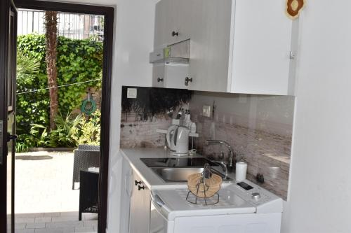 a white kitchen with a sink and a stove at Studio apartman Tasha in Opatija