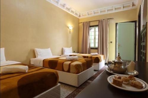 Habitación de hotel con 3 camas y mesa en HOTEL CTM, en Marrakech
