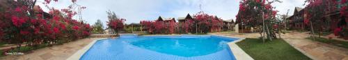 a large blue swimming pool in front of a house at ChaleVille coqueiro - Chalé 2101 in Luis Correia