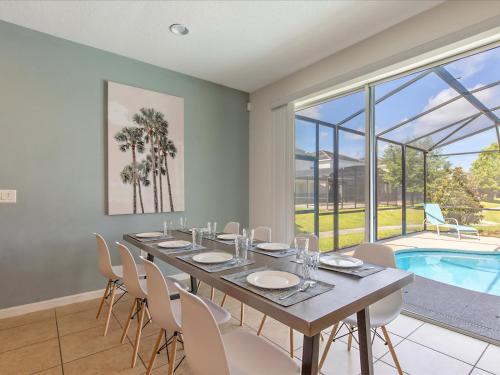 a dining room with a table and chairs and a pool at 6BR w Heated Pool + 9MI to Disney + Sleeps 14 in Kissimmee