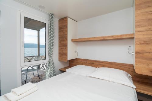 a bedroom with a white bed and a window at Amadria Park Camping Sibenik Mobile Homes in Šibenik