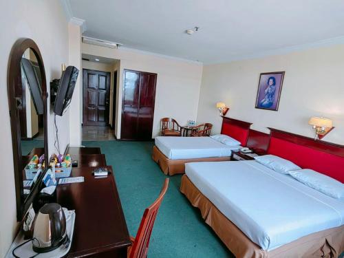 a hotel room with two beds and a desk at PIA Hotel Bandung in Bandung
