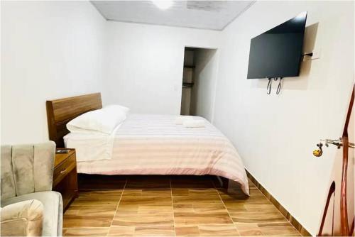 - une chambre avec un lit et une télévision murale dans l'établissement Villa Mongui, à Monguí