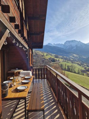 a wooden table on a balcony with a view of mountains at Chalet de Manigod in Manigod