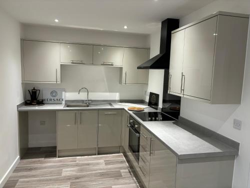 una cocina con armarios blancos y electrodomésticos de acero inoxidable en Versace The Malt House, en Burton upon Trent