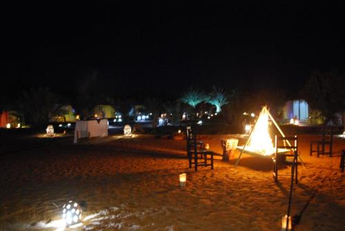 a lit up tent on a beach at night at Hamada Activities Luxury Camp in Merzouga