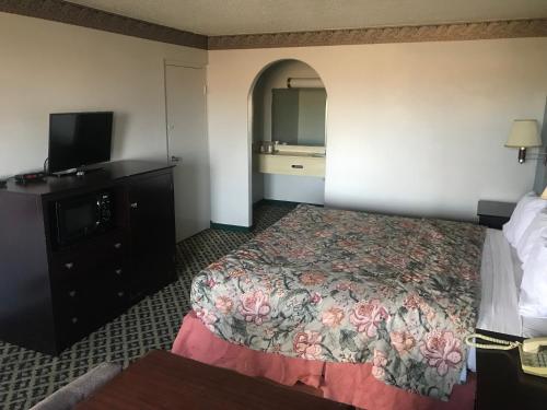 a hotel room with a bed and a flat screen tv at executive inn & suites in Lufkin