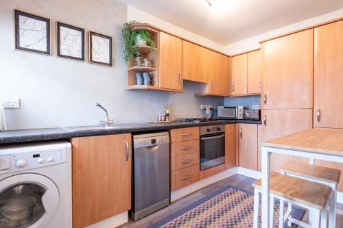 a kitchen with wooden cabinets and a washer and dryer at The Tartan Terrace in Inverness