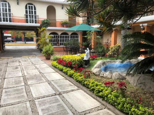 un jardín con una fuente y flores frente a un edificio en Hotel Mezvall en Morelia