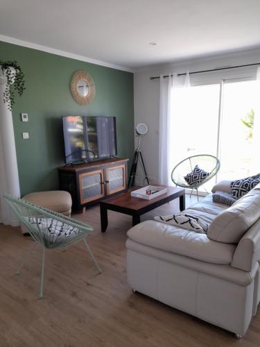 un salon avec un canapé et une télévision dans l'établissement maison proche mer et foret, à Olonne-sur-Mer
