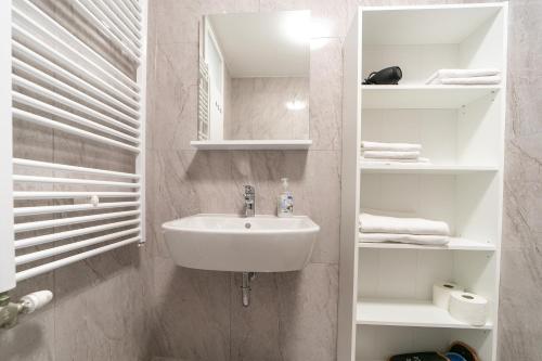 a white bathroom with a sink and shelves at Katia in Zagreb
