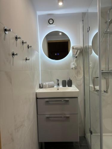 a bathroom with a sink and a shower with a mirror at Domek Bałtycki Lux in Rewa