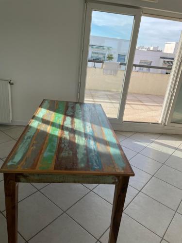 une table en bois assise dans une pièce avec fenêtre dans l'établissement Appartement Lyon, à Lyon