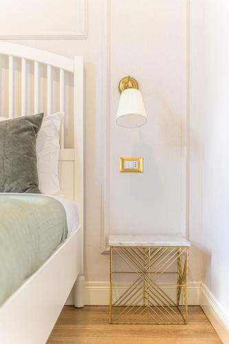 a white bedroom with a bed and a side table at L'Opera Rooms & Suite in La Spezia