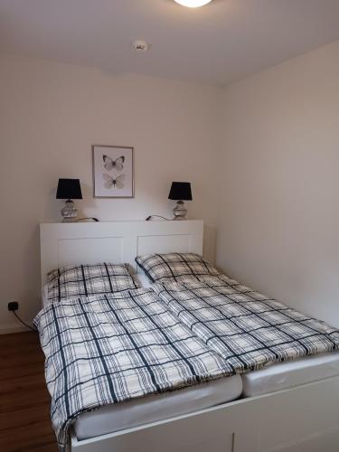 a white bedroom with a bed with two lamps at HARZ-LIEBE Lautenthal in Langelsheim