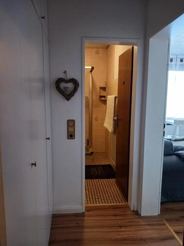 a hallway leading to a bathroom with a heart clock on the wall at HARZ-LIEBE Lautenthal in Langelsheim