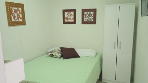 um quarto com uma cama com duas fotografias na parede em POUSADA MEGA em Marataízes