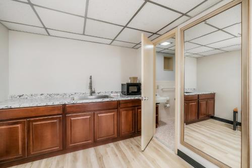 a kitchen with wooden cabinets and a sink and a mirror at Extended Stay Suites Cookeville - Tennessee Tech in Cookeville