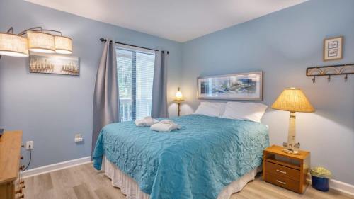 a bedroom with a bed with a blue blanket and a window at Walk to the Beach Waterfront Oasis in Hilton Head Island