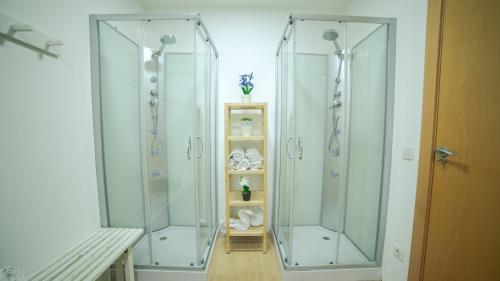 two glass showers in a bathroom with a shelf at Only Women Guest House - Villa de la Comunidad Internacional de la Mujer in Olivella