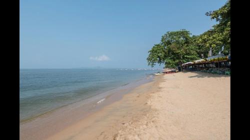 a sandy beach with trees and the ocean at Heartbeat Crypto Jomtien 05 in Jomtien Beach