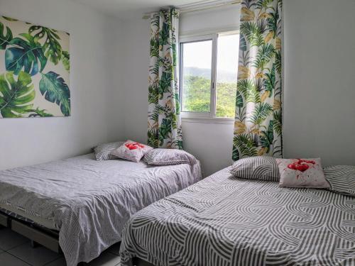 1 dormitorio con 2 camas y ventana en Villa Mimi, en Saint-Louis