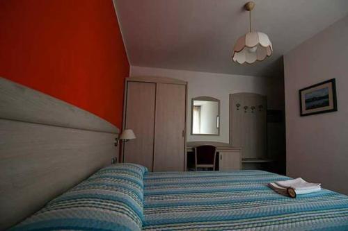 1 dormitorio con 1 cama con manta de rayas azules en Albergo Mezzolago, en Pergine Valsugana