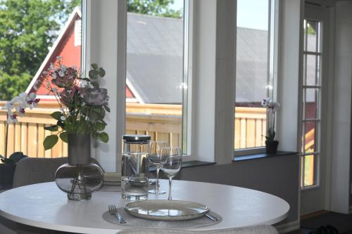 a table with wine glasses and a vase with flowers at Apartment Berghem Grönadal Nättraby in Nättrabyhamn