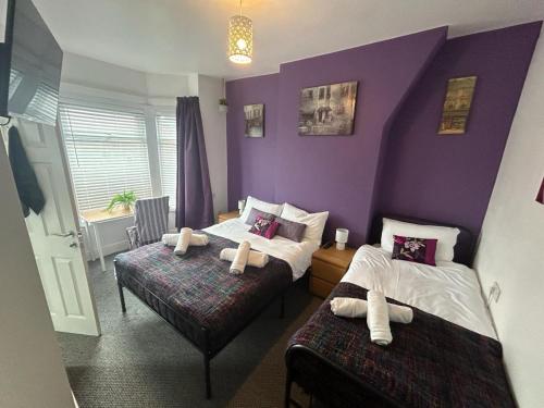 a bedroom with two beds and a purple wall at West Street House in Crewe
