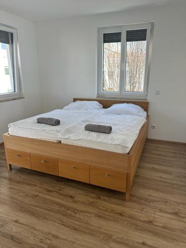 a large bed in a room with two windows at Neubauwohnung gleich bei der Bushaltestelle - Apartment 2a in Vienna