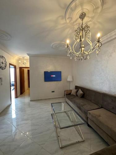 un soggiorno con divano e lampadario pendente di Al Hoceima Mini Villa ad Al-Ḥoseyma
