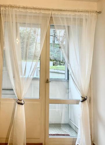 Cette chambre dispose d'une fenêtre avec des rideaux blancs. dans l'établissement Location Studio, Lyon-la Mulatière, à La Mulatière