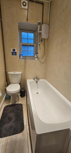 a bathroom with a white tub and a toilet at Kensington Guest Rooms 98 in London