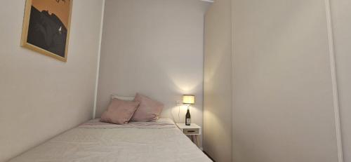 Dormitorio pequeño con cama y lámpara en Confortevole stanza privata in grazioso appartamento con giardino, en Cagliari