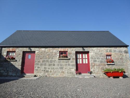 a stone house with red doors and flowers on it at Minnie’s Cottage 
