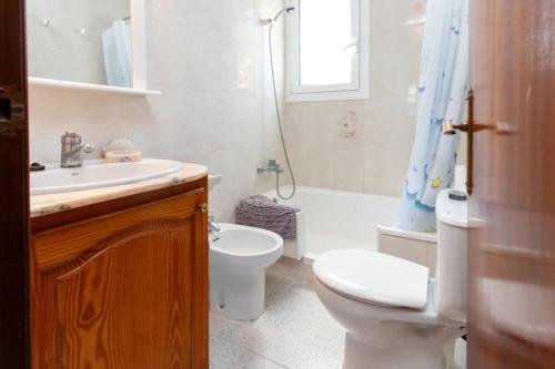 a white bathroom with a toilet and a sink at Apartamento en S agaró zona tranquila in S'agaro
