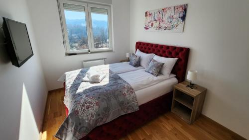 - une chambre avec un lit doté d'une tête de lit rouge et d'une fenêtre dans l'établissement Ada Nostra, à Banja Luka