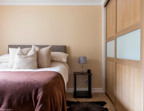 a bedroom with a bed with white pillows and a window at The Apartment at No.12 in Lochwinnoch
