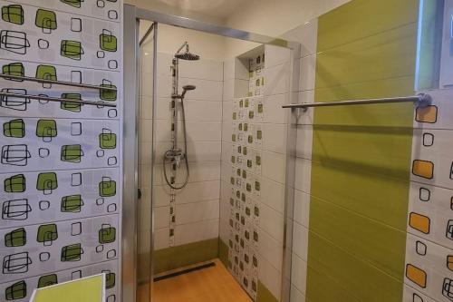 a bathroom with a shower with green and white tiles at Apartmán u Aničky in Banská Bystrica