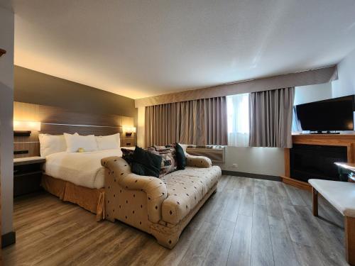 a hotel room with a bed and a couch at Days Inn by Wyndham Penticton Conference Centre in Penticton