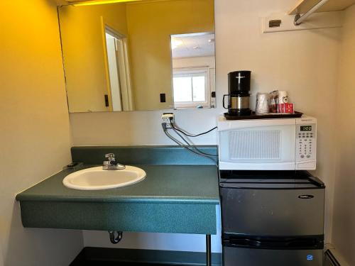 een badkamer met een wastafel en een magnetron bij White River Motel in White River