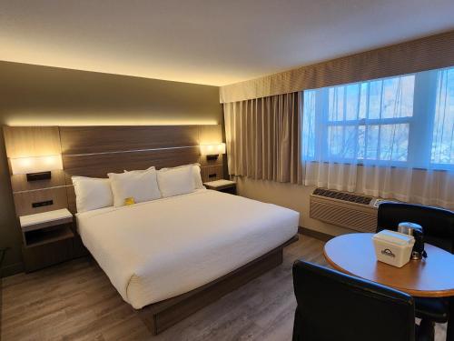 a hotel room with a large bed and a table at Days Inn by Wyndham Penticton Conference Centre in Penticton