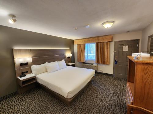 a hotel room with a large bed and a window at Days Inn by Wyndham Penticton Conference Centre in Penticton