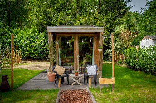 um gazebo com uma mesa e cadeiras num quintal em Tiny House Hilver - uniek en sfeervol huisje middenin het bos em Diessen