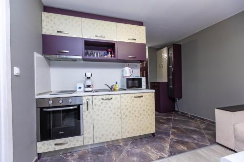 a kitchen with a stove and a microwave at Апартаменти Елеганс in Sandanski