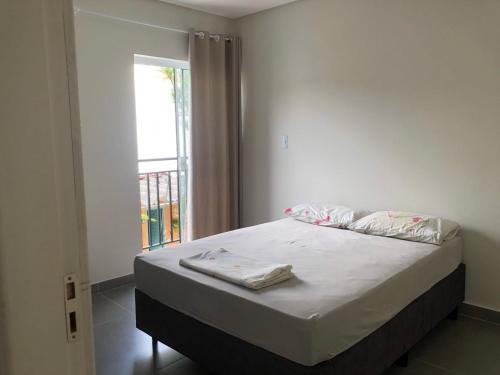 a bedroom with a bed and a window with a balcony at Apto 70m² no centro de Porto Belo in Porto Belo