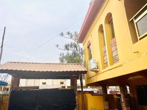 a yellow building with a gate next to a house at Villa de chez nous in North Legon
