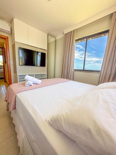 a bedroom with a large white bed with a window at Itacimirim Apartments Boulevard e Ondas in Itacimirim