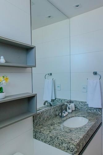 a bathroom with a sink and a mirror at Itacimirim Apartments Boulevard e Ondas in Itacimirim