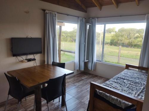 a dining room with a table and a television at Cabañas La Retama in Tandil